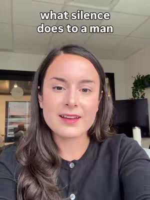 A woman with long brown hair is positioned in front of a soft-lit interior. Text overlay indicates the video's subject. She's wearing a black button-down shirt.