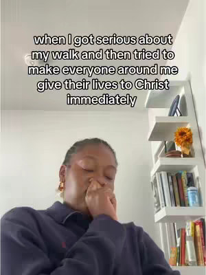 A woman in a dark blue collared shirt covers her mouth with her hand and looks down. Above her is text, set against a light background with white shelves holding books and decorative items.