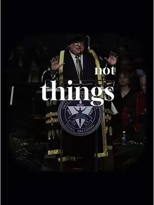 The image captures a man in a formal setting seemingly delivering a speech. He stands behind a podium with the seal of 'Oral Roberts University' prominently displayed. Overlayed on the image is the text 'things not'. The man is wearing a suit with a tie. The background appears dark with other figures slightly visible.