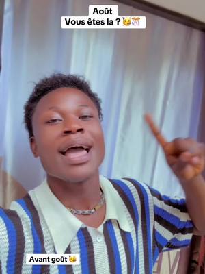 A young man with dark hair and skin is positioned in front of what looks like a white curtain. He is wearing a short-sleeved shirt with blue and white horizontal stripes. His expression is animated, with his mouth open as if speaking, and he's pointing one finger up towards his right. Text appears in a white box at the top of the image and another at the bottom.