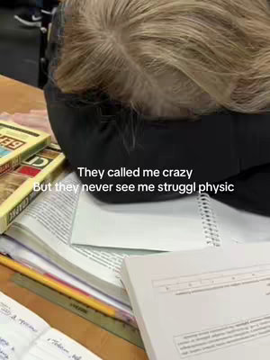 The cover image shows a person's head resting on a desk covered in open books and a pencil. The person's hair is blonde, and a black garment covers the top of their head. Text is overlaid on the image.