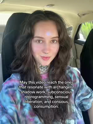 A woman with long wavy brunette hair is seated in a car, looking directly at the camera with a slight smile. Her face is the main focus, with soft lighting highlighting her features. Text is overlaid on the image, stating the video's focus.