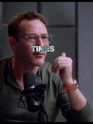 A man wearing glasses is positioned in front of a microphone. The text overlay 'TIMES' is across the center of his face.