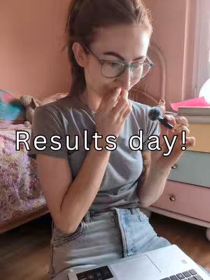 A young woman with glasses, possibly in a bedroom environment, is holding a microphone in her right hand and covering her mouth with her left hand. She appears to be in a moment of anticipation or surprise. The text overlay reads 'Results day!' in white font, placed centrally over her torso.