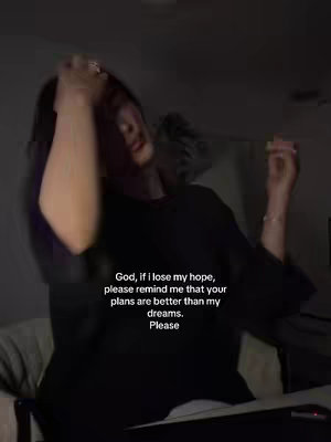 A dimly lit image shows a person with long dark hair holding their hand up to their head, appearing to be either fixing their hair or resting their hand on their head. The person is wearing a dark-colored top, and the background is out of focus, but contains a blurred-out, light-colored area on the left, and is otherwise dark. Overlaid on the image is a white text that provides a powerful message.