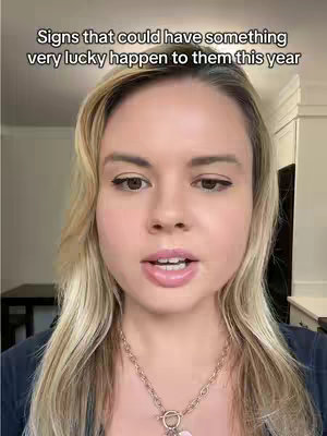 A woman with blonde hair and wearing a black top is centered in a medium shot. The background is blurred but appears to be a room with a light color scheme. Overlayed at the top of the image is text in white font.