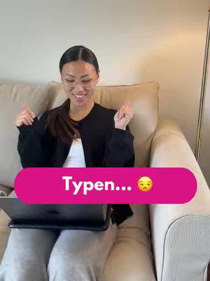 A young woman with a ponytail and glasses smiles and gestures on a cream-colored couch. A laptop rests on a tray in her lap. A pink rectangular graphic with the text 'Typen...' and a sad face emoji is overlaid on the image.