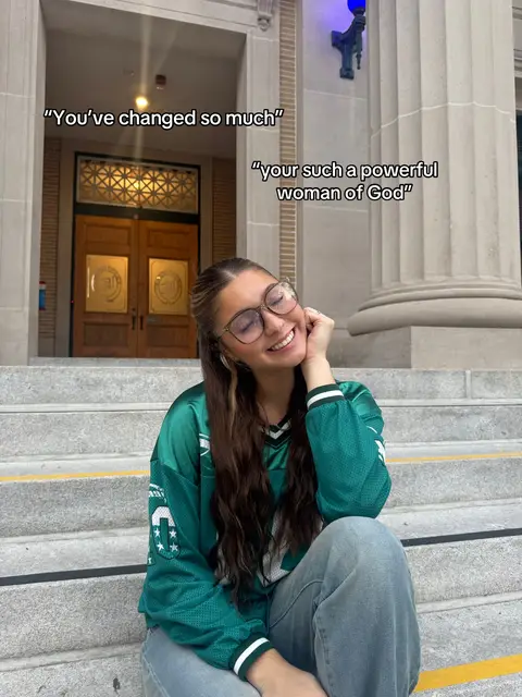 A woman with long brown hair wearing a green jersey and glasses smiles on a set of concrete steps. Text overlays on the left state "You've changed so much" and on the right "your such a powerful woman of God". The background includes a large building entrance with pillars.