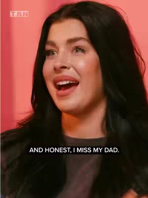 A woman with long black hair is looking up and to the side with her mouth open as if she is speaking or surprised. She is in front of a pink background. The text overlayed on the image says 'AND HONEST, I MISS MY DAD.'