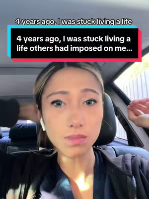 The cover image is a selfie-style video, with the creator, a woman with light hair pulled back, centered in the frame. She's sitting in what appears to be the front seat of a car, with the interior visible in the background. Above her head is a text overlay in a rectangular box, with a turquoise background and white text. The woman has a slightly pensive expression, with her eyes directly facing the camera.