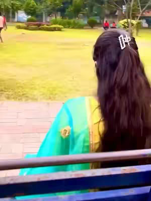The cover image shows a woman from the back, facing away from the camera, in a park setting. She is wearing a turquoise and yellow outfit with a decorative hair clip. The background features a grassy area with trees, other people, and a bench.