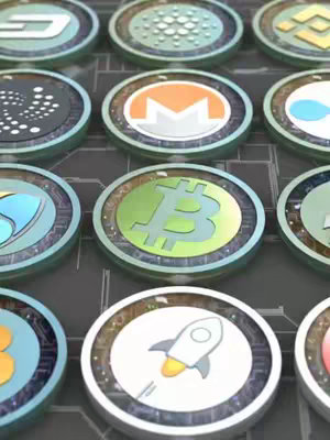 The cover image features a grid of circular tokens against a blurred background. These tokens represent various cryptocurrencies, with prominent logos like Bitcoin (BTC), Monero (XMR), and others. The tokens have a shiny, metallic look, and the background is a dark color with subtle lines