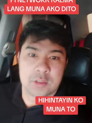 A man is sitting inside a car filming a video. There are text overlays on the image in red rectangular boxes. The man is looking directly at the camera and appears to be speaking.