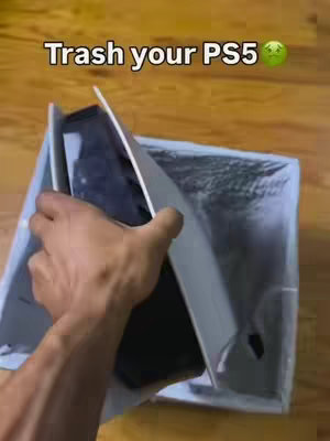 A hand is shown pulling a PlayStation 5 console from a box, suggesting the console is being discarded. Above, the text "Trash your PS5" is displayed with a green emoji of a vomiting face.