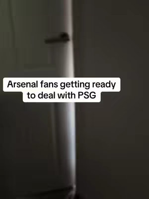 The image is a vertical shot of what appears to be a hallway. A white vertical pipe, possibly a water pipe, runs down the center of the frame. To the sides are what looks like white walls. A textual overlay at the center includes the text: "Arsenal fans getting ready to deal with PSG". The lighting is dim, creating a moody and slightly mysterious atmosphere.