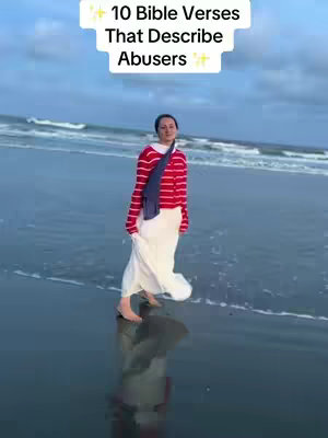A woman in a red and white striped shirt and a long white skirt walks on the beach in an overcast setting. The waves are gently lapping at the shore. Text overlay is set at the top of the frame.