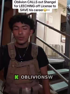 A young man with short, dark curly hair is centered in the image, looking directly at the camera with a neutral expression. He is wearing dark clothing with a strapped vest on top. The background suggests an interior setting with stairs, a door, and miscellaneous objects. Text overlays across the top and bottom of the image, giving context to the video's content.
