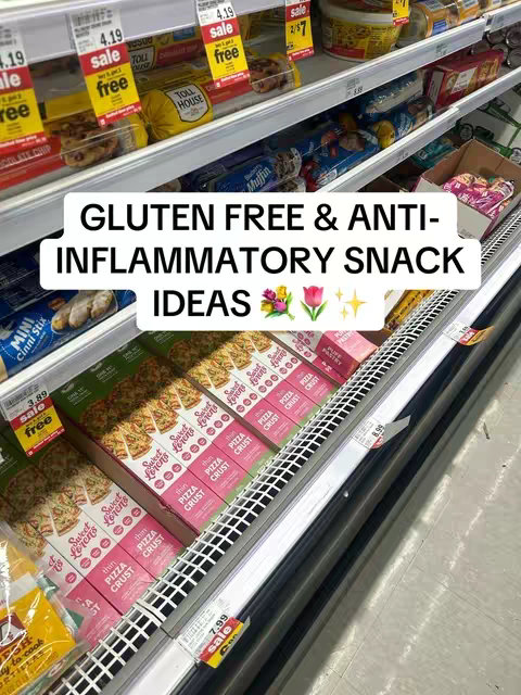 The image shows a refrigerated section of a grocery store filled with various products. In the foreground, boxes of what appears to be gluten-free pizza crust are prominently displayed. Above, shelves are stocked with other items including snacks, and sale signs. The text overlay reads "GLUTEN FREE & ANTI- INFLAMMATORY SNACK IDEAS". The composition features a bright, well-lit setting with an emphasis on the packaged food products.