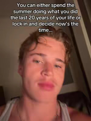 A young man with light brown hair appears in a selfie-style video, with text overlayed on the image. The background is dimly lit, and there is a slight tilt to the image, creating a sense of intimacy.