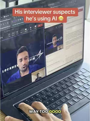 The image shows a laptop screen split in two. On the left, a man is shown in a video call, looking animated and speaking. The screen shows the Lockheed Martin logo in the background. On the right side of the laptop screen, another window shows the man in a smaller video call window and appears to be reading text. In a red bar at the top it's written: His interviewer suspects he's using AI. At the bottom of the screen under the keyboard a text overlay says: WAY TOO GOOD. The background is a light-colored wall, next to the laptop keyboard and the hand is pressing a key.