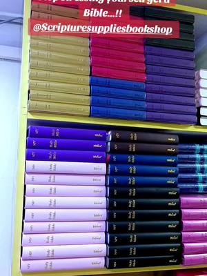 The image showcases a display of various Bibles neatly arranged on shelves. The books have covers in different colors like red, blue, yellow, black, and pink. Above, there's a text overlay in red. The composition is a straight-on shot, showing the organization and variety of the Bible selection.