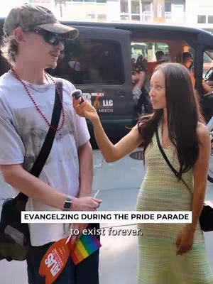 A woman interviewing a man at a Pride Parade. The woman is holding a microphone and the man is wearing sunglasses and a baseball cap.
