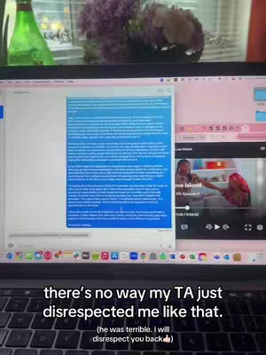 A laptop displays a blue-tinted document, another application with a video segment, and a show is playing showcasing two people.  A text overlay is visible toward the bottom.  Above the computer, out of focus, are what appear to be flowers. The laptop keyboard is prominent in the foreground.