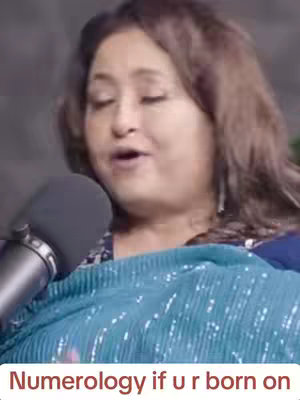 The cover image features a woman with brown hair partially covering her face. She is speaking into a microphone with her eyes closed. Overlayed text at the bottom reads "Numerology if u r born on". The background is a muted, undefined color.