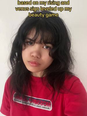 A close-up shot of a person with long, dark hair and eyes looking at the camera with a neutral expression. The person wears a red t-shirt. The background is a plain white wall, and text overlays the top of the image.