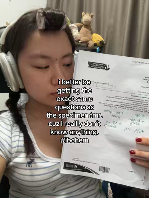 A young woman with headphones and hair rollers holds a document. Text overlays on the image convey the video's message about an exam.