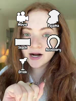A woman with long reddish-brown hair looks directly at the camera, with several illustrated icons overlaid around her face, suggesting a movie night theme, including a movie camera, pajamas, a snack, an accessory, and a drink. She is pointing with one hand that has rings on the fingers. The background has a room and a lamp with soft lighting.