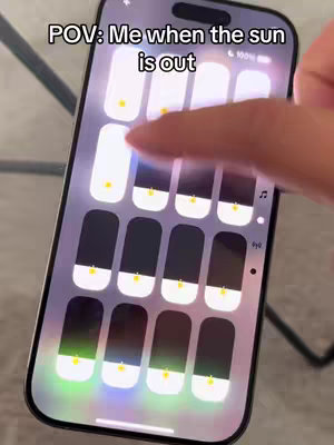 A phone screen displaying the control panel, with the brightness bar adjusted. A finger is pointing at the brightness bar.