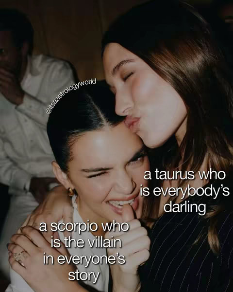 The image shows two young women of fair complexion engaged in an affectionate moment. The woman on the right is embracing the other, kissing her on the cheek. The woman being kissed is winking and biting her lip. Text overlays describe the women's zodiac signs and associated personality traits, such as "Scorpio who is the villain in everyone's story" and "Taurus who is everybody's darling."