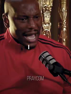 The cover image showcases a close-up of a man, Tyrese, speaking into a microphone. He is wearing a red track jacket. The lighting appears to be warm, highlighting his face. The microphone is black. The background has ornamental gold features. The text "PRAY.COM" is seen at the bottom.