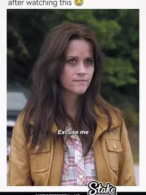 The image features a woman with brown hair, wearing a yellow jacket over a plaid shirt. She has a somewhat annoyed or puzzled expression. Text overlays include the phrase "Excuse me", and a logo at the bottom right corner. The background appears blurry.