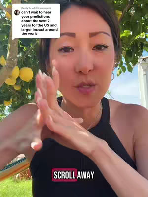 A woman with fair skin, brown hair, and a black top is centered in the frame. She stands outside with green foliage and yellow fruit behind her. She's holding her hands up in a gesture of clapping. The video overlay says "Scroll Away". A square is in the top left corner with a comment from someone asking about predictions.
