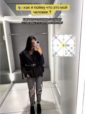A young woman in a full-length mirror selfie, wearing a black blazer, distressed jeans and black boots. The background is a plain, industrial-looking space. Two lines of white text overlaid on the upper part of the image, with a diagram to the right.