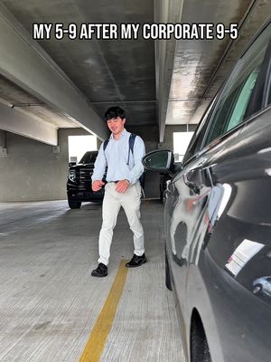 A photo shows a young man walking out of a parking garage. The man is wearing a light blue button-down shirt, white pants, and black shoes, and he has a backpack over one shoulder. The parking garage is brightly lit, and there are cars parked on either side of him. In the background, there's a black pickup truck.