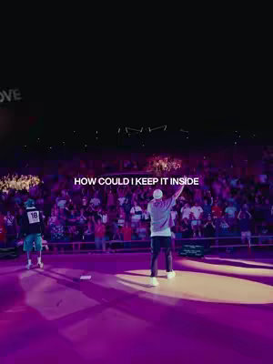 A live music stage setup at the Red Rocks venue, with a performer center stage, arms raised, in front of a crowd. Text overlayed at the bottom provides a caption.