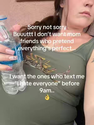 The image is a selfie-style shot of a person holding a water bottle partially visible on the left. The person is wearing a green top with a decorative emblem. The text overlayed on the image includes the phrases 'Sorry not sorry,' 'I don't want mom friends', and 'I want the ones who text me "I hate everyone" before 9 am' arranged in white text. A hand holding the bottle is visible, and the image has a natural lighting.