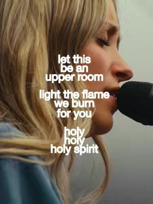 A side profile shot of a woman with blonde hair singing into a microphone. Text overlays the image with lyrics in white font.