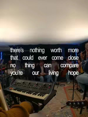 A vertical cover image shows a room with a band setup. A keyboard is in the foreground, with a person's arm and hand holding it. In the background, there is a group of people, some playing instruments. Overlayed on the top part of the image is a white text with the lyrics about hope and the presence of the lord.