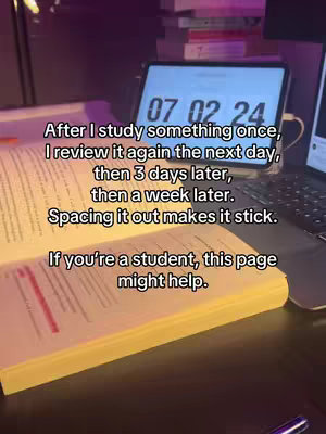 A close-up shot of an open book with handwritten notes, a digital tablet displaying a clock, and a laptop in the background indicating a study setup. The lighting is dim with warm tones.