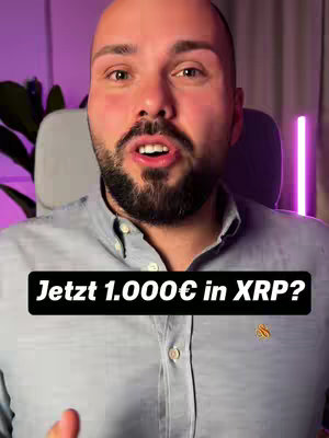 A man with a dark beard and short hair looks at the camera with an open mouth. He's wearing a light blue shirt and is positioned in front of a blurred background with purple lighting. A black banner with white text lays across the bottom of the view.