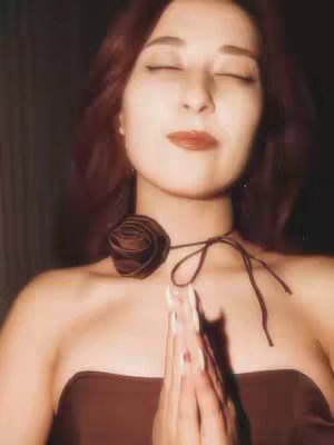 The cover image features a woman with auburn hair and closed eyes, wearing a brown strapless top and a brown rose choker. Her hands are clasped in front of her chest. The background is dark, creating a soft, warm, and slightly vintage aesthetic.