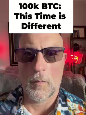 A man with a bald head, glasses, and a beard is centered in the frame, with text above his head indicating the video's topic. The background is blurred, with hints of a room setting.