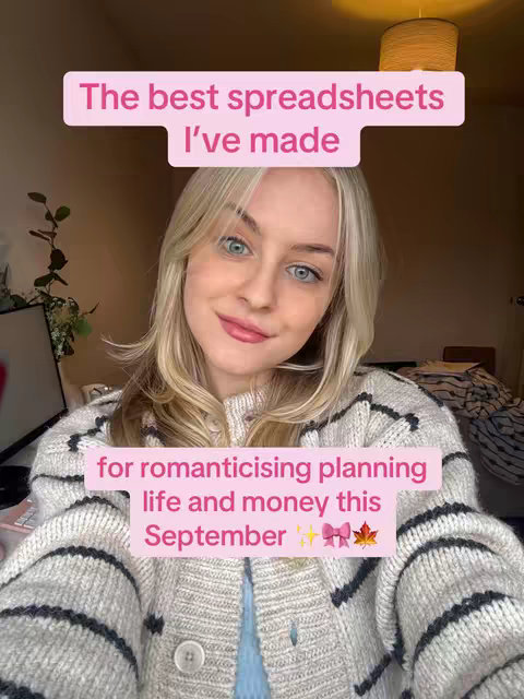 A woman with blonde hair smiles at the camera. Text overlays in pink rectangles state: "The best spreadsheets I've made" and "for romanticising planning life and money this September ✨🎀 🍁". The background is softly lit with a neutral palette. She is wearing a light gray cardigan with dark gray stripes and a light blue top underneath.