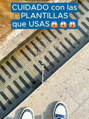 The image shows a close-up of a water drain with water flowing through it from the top. A pair of white sneakers trimmed with black and blue accents are visible at the bottom of the image. Above the drain, text in a blue box saying 'CUIDADO con las PLANTILLAS que USAS' with three astonished face emojis.