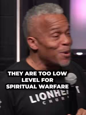 A man with short, graying hair and a dark shirt speaks into a microphone. Text overlays read "THEY ARE TOO LOW LEVEL FOR SPIRITUAL WARFARE". The man appears to be in a studio setting, lit with neutral lighting. There are dark colors.
