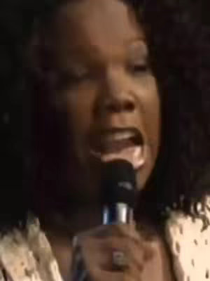 The cover image features a close-up of a Black woman singing enthusiastically into a microphone. She appears to be mid-performance, mouth open wide, with a look of passion and focus. The background is blurred, suggesting a performance setting.